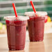 A couple of plastic cups with red Fresh Blends Wildberry beverage in them with straws.