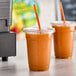 Two cups of Fresh Blends Organic Carrot Ginger beverage with straws.