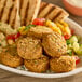 A plate of Peppo Foods gluten-free falafel balls with pita bread and vegetables.