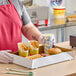 A man in a red apron holding a white U-Type Donut Tray full of fast food.