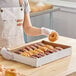 A person holding a box of donuts in a U-Type donut tray.