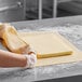 A person in gloves rolling out Isigny Sainte-Mere unsalted butter lamination dough on a counter.