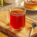 A glass mug of brown Cinnabon coffee on a wooden board with a spoon.