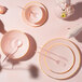 A table set with a Posh Setting pink plastic coupe plate, fork, and spoon.