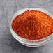 A white bowl filled with red Cholula Chili Lime Seasoning powder.