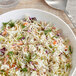 A bowl of coleslaw with carrots and celery on a white background.