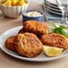 A plate of three crab cakes with lemon wedges on the side.