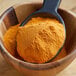 A spoonful of Lawry's Mango Habanero seasoning mix powder in a wooden bowl.