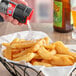 A hand using a black and red McCormick Sea Salt Grinder to sprinkle salt on french fries.