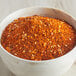 A bowl of red and black spices on a wooden table.