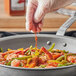 A person pouring McCormick Culinary Ground Red Pepper onto shrimp in a professional kitchen.