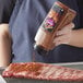 A person pouring McCormick Mesquite seasoning on a piece of meat.