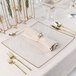 A table setting with Posh Setting clear charger plates with gold rims, silverware, and a napkin.