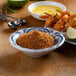 A bowl of McCormick Cajun seasoning and a plate of shrimp on a table.