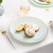 A Posh Setting turquoise plastic coupe plate with a gold band holding cookies and lemon wedges.