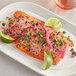 A plate of food with a piece of salmon and vegetables with a lime on the side.