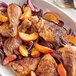 A plate of food with a piece of chicken, fruit, and spices on a table.