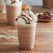 A close-up of a cup of Big Train chocolate peanut butter blended ice coffee with whipped cream and chocolate drizzle.