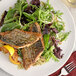 A plate of salad and fish with McCormick Culinary Lemon 'N Herb seasoning on a table with a fork.