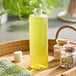 An 8 oz. clear PET cylinder bottle of yellow liquid on a table.