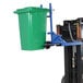 A blue forklift with a green garbage can attached using a chain.