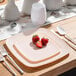 A Posh Setting pink plastic square coupe plate with a gold band on it with strawberries.