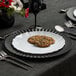 A Posh Setting white plastic plate with silverware and cookies on it.