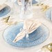 A table set with Posh Setting blue plastic coupe plates with gold napkins on them.