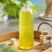 A 16 oz. clear Cosmo Bullet PET bottle of liquid on a tray with a green leaf.