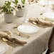 A table set with white Posh Setting clear plastic plates with gold bands and gold cutlery.