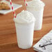 Two cups of white Big Train Vanilla smoothies with whipped cream and straws.