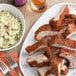 A white plate with a piece of meat, coleslaw, and a fork.