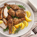 A plate of food with lemons, chicken, and herbs.