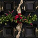 A table with black square Posh Setting plastic plates with gold trim.