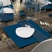 A table set with blue napkins and Posh Setting navy charger plates.