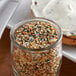 A jar of McCormick Culinary Everything Bagel Seasoning on a table next to a slice of bread.