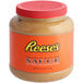A Reese's Peanut Butter Sauce jar on a table in a grocery store aisle.