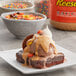 A brownie with ice cream and REESE'S Peanut Butter Sauce with a bowl of candy.