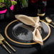 A table set with a Posh Setting clear charger plate with gold rim, black and gold cutlery, and black and yellow glassware.