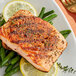 A plate of grilled salmon with lemon slices and green beans with a fork.