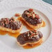 Three pastries covered in Ghirardelli caramel sauce on a plate.