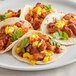 A plate of tacos with meat and vegetables topped with McCormick Culinary Ground Cayenne Pepper.