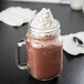 A glass mug of Ghirardelli Frozen Hot Cocoa Frappe Mix with whipped cream on top.