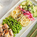 A plate of noodles, salmon, and vegetables with black sesame seeds on top.