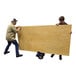 Two men using a Vestil heavy-duty slab dolly to move a large wooden board.