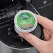 A hand placing a Green Mountain Coffee Colombia Select K-Cup Pod into a coffee machine.