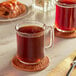 Two glass mugs of brown liquid on a table.