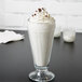 A glass of Ghirardelli White Mocha Frappe on a table with whipped cream and chocolate chips.