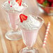 Two glasses of Big Train strawberry frappes topped with whipped cream and strawberries.