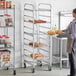A woman standing in front of a Winholt sheet pan rack in a kitchen.